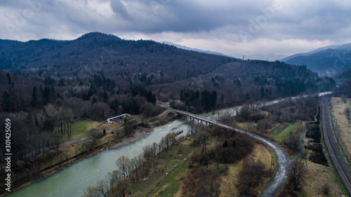 Aerial drone view of green mountain, pine forest, river and village. Carpathian, Ukraine.