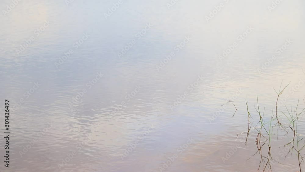 Dreamy view of the sky and clouds reflection on the water surface with gentle soothing ambient motions of ripples showing tranquility and mindfulness Dreamy view of the sky and clouds reflection on the water surface with gentle soothing ambient motions of ripples showing tranquility and mindfulness