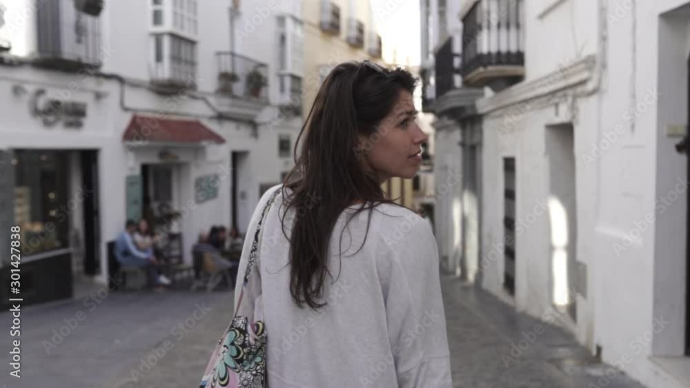 Young women walks down shopping street in Gibraltar, Spain, looking around at shops. Camera follows from behind. Young women walks down shopping street in Gibraltar, Spain, looking around at shops. Camera follows from behind.
