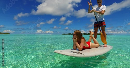 Sweet Couple Enjoy The Vacation Beach Through Paddling with Exotic Island and Calm seas At The Background in Mexico - Steady Shot photo