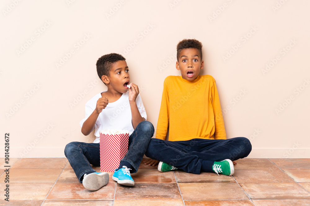 African American brothers holding popcorns and doing surprise gesture African American brothers holding popcorns and doing surprise gesture