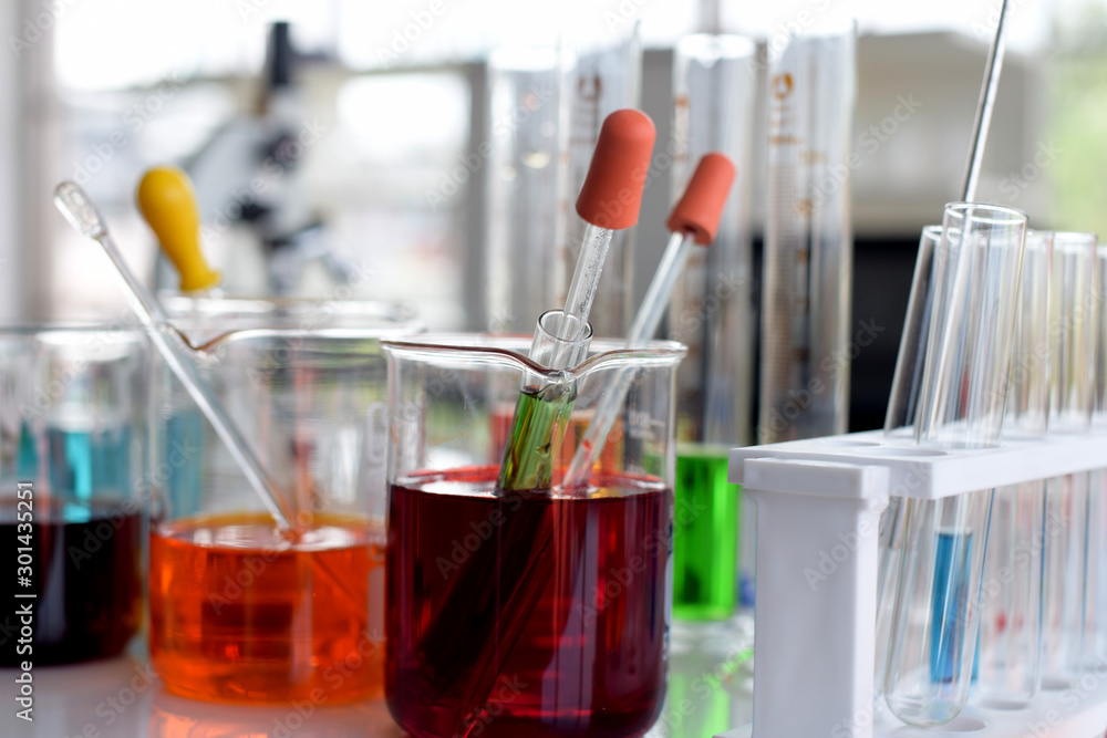 glass test tubes and flasks with colorful liquid on blue background with molecular structure glass test tubes and flasks with colorful liquid on blue background with molecular structure