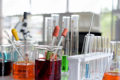 glass test tubes and flasks with colorful liquid on blue background with molecular structure