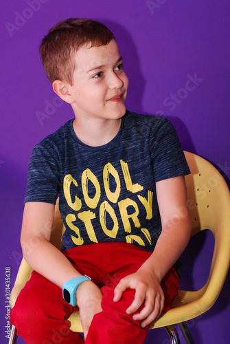 portrait of a pretty boy sitting on a chair in the studio