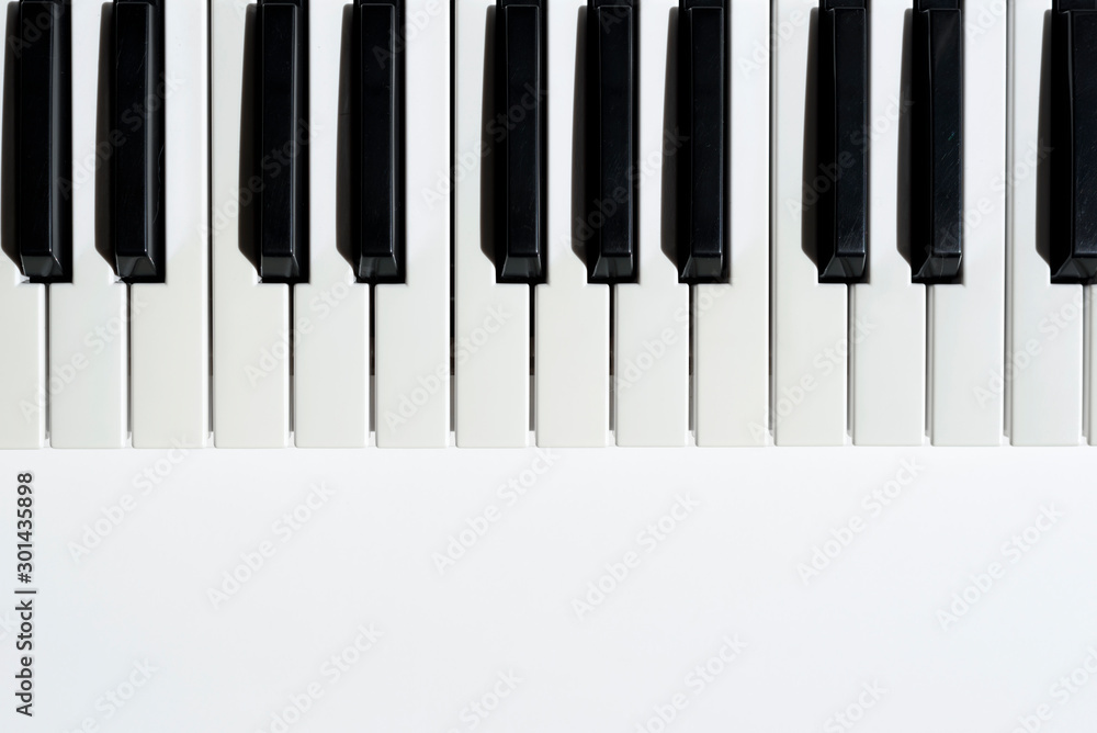 Top view of keyboard instrument on white background with copy space under it. Black and white keys of piano. Top view of keyboard instrument on white background with copy space under it. Black and white keys of piano.