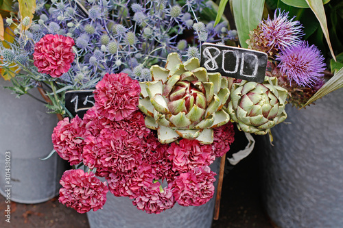 Pink carnations, artichokes and blue heads at market photo