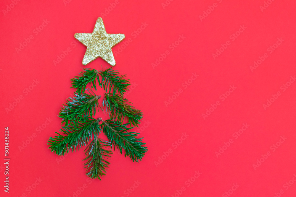 Creative Christmas tree made of pine tree branches and golden star on red background Creative Christmas tree made of pine tree branches and golden star on red background