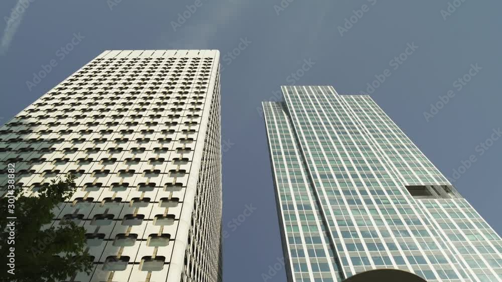 Two Skyscrapers with green glass windows at business district in Paris, low angle tracking out, wide shot with reflections. Futuristic modern building in Blue Sky. 4K UHD. White and green. Two Skyscrapers with green glass windows at business district in Paris, low angle tracking out, wide shot with reflections. Futuristic modern building in Blue Sky. 4K UHD. White and green.