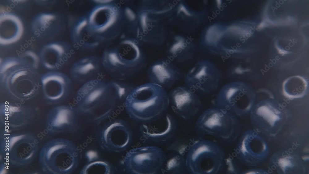 Pouring dark blue beads into a white plate. Pouring dark blue beads into a white plate.