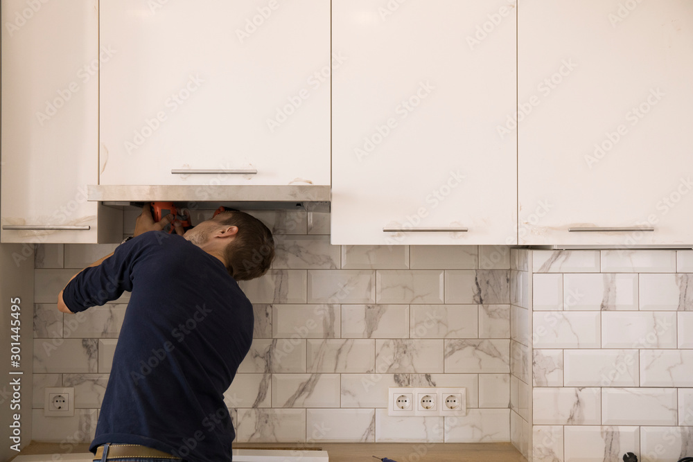Handyman assemblying home range hood in kitchen furniture