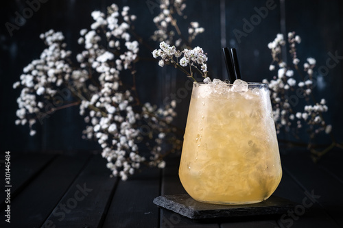 A refreshing cocktail with pineapple in a glass with ice and flowers