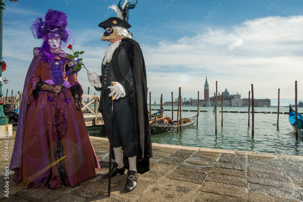 Couple homme et femme costumé de noir et de violet devant le grand canal au carnaval di Venise en Italie 