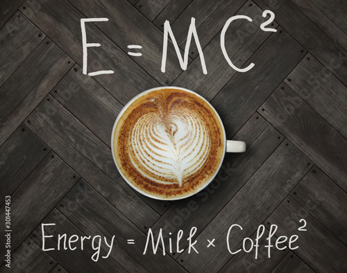 The cup of black energy coffee with milk and two funny formulas. Wooden backg...