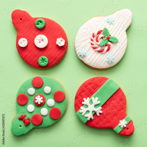 Christmas cookies, colored gingerbread globes with buttons and snow flakes on green background