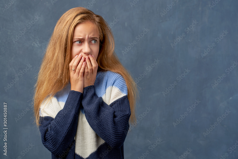 Teenage girl blonde in warm sweater isolated wall Teenage girl blonde in warm sweater isolated wall