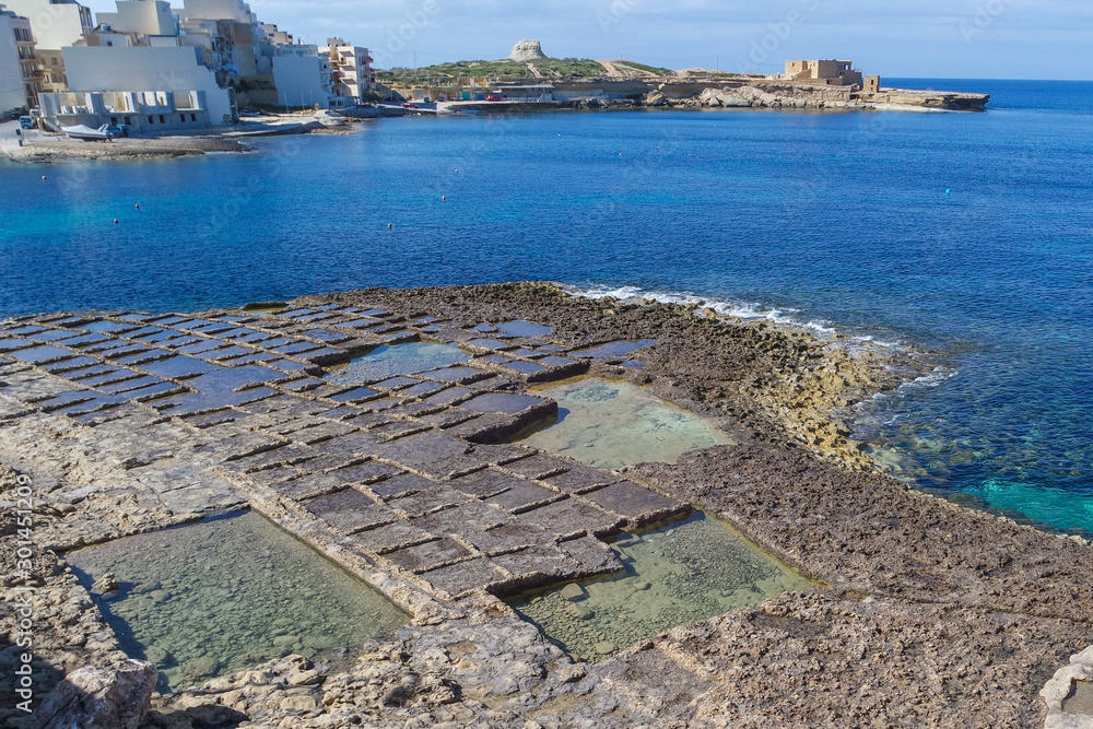 Salt pans along the waterfront with the Il-Qolla I-Badja battery, Marsalforn, Gozo, Malta, Europe