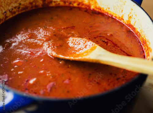 Photos Pot of slow cooked marinara with wooden spoon.