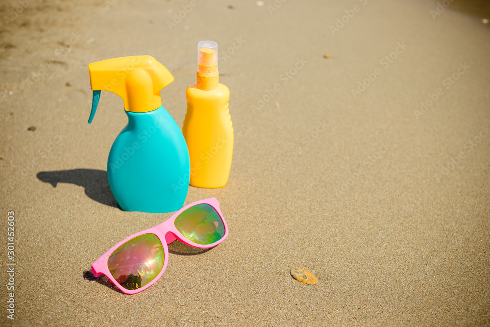 sunscreen, glasses on sand beach background. Cosmetics for safe sunburn. Skin care concept. Healthy skin on vacation.Trip accessoriesfor happy and healthy holidays - sunglasses, sunscreen solar lotion