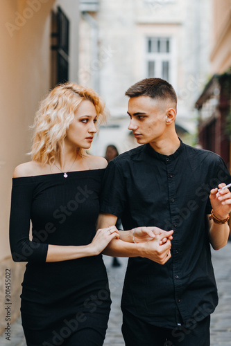 Stylish couple walking down the street, holding hands, looking at each other