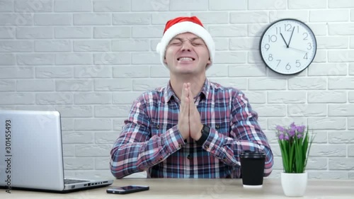 Young man in santa hat making a wish for Santa keeping his fingers crossed. Fingers crossed, make a wish concept