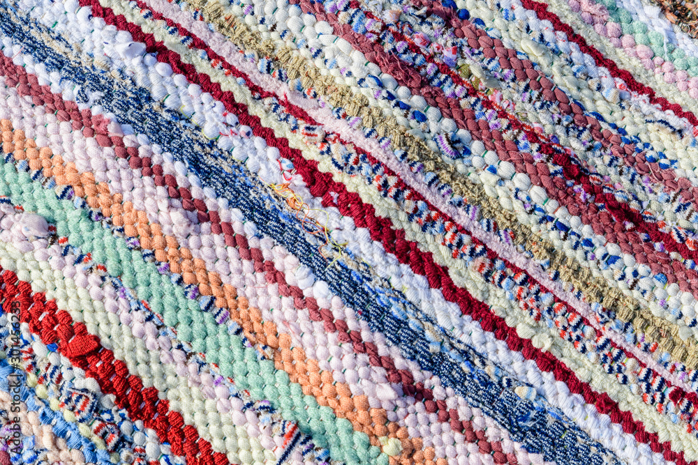 Background of manually woven textile materials of different colours, red, green, yellow, blue, green and pink pieces, with diagonal lines, photographed with soft focus