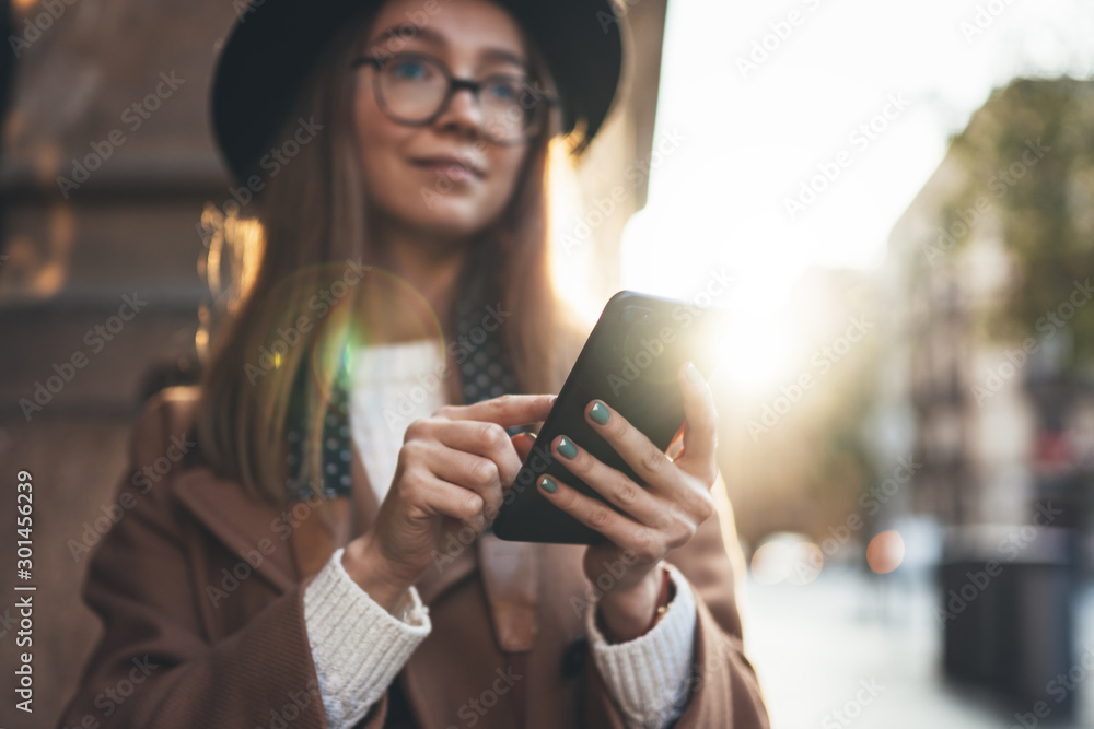 Traveler woman holding in hands mobile phone. Close up technology smartphone online connect. Girl hipster in glasses using gadget cellphone in europe sun flare city. Digital internet lifestyle mockup