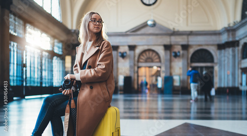 Tourist photographer woman with suitcase on platform station in Barcelona. Girl traveler waiting train enjoy holiday weekend vacation in transport railway. Travel railroad station concept