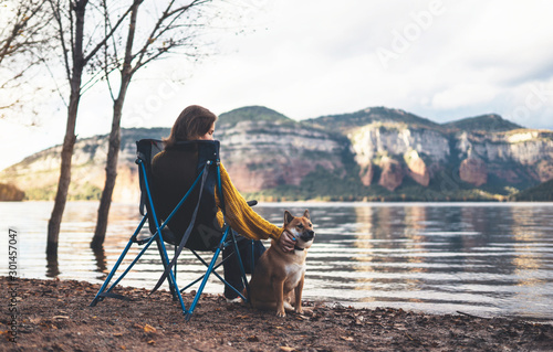 tourist traveler girl relax together dog on background mountain, puppy pet with woman rest on lake shore nature trip, friendship concept © A_B_C