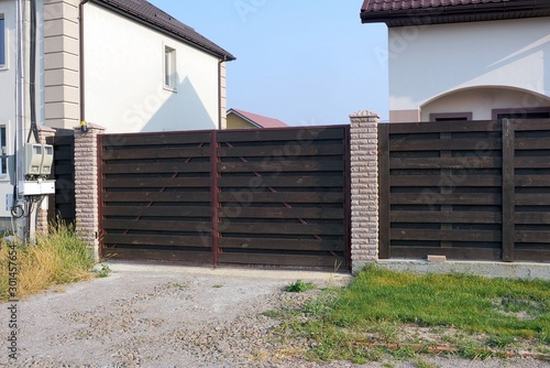  closed brown gate made of wooden boards on a rural street
