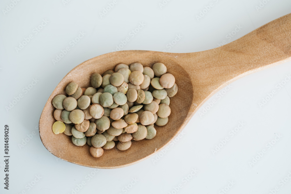 green lentil in a wooden spoon. on white background green lentil in a wooden spoon. on white background
