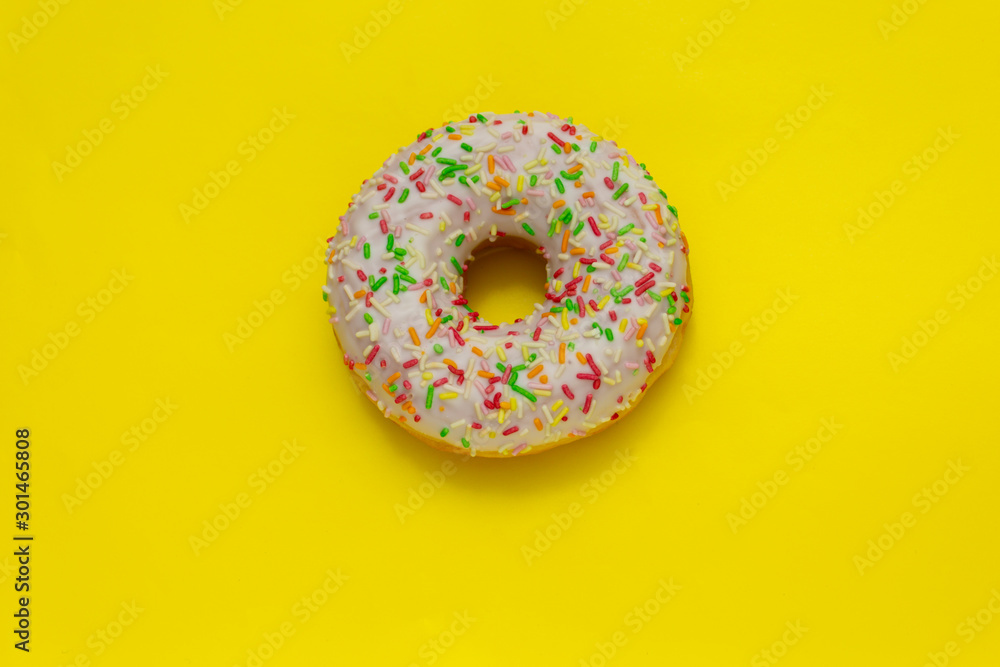 donut with colored sugar sprinkles on yellow background donut with colored sugar sprinkles on yellow background