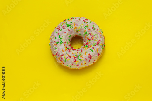donut with colored sugar sprinkles on yellow background