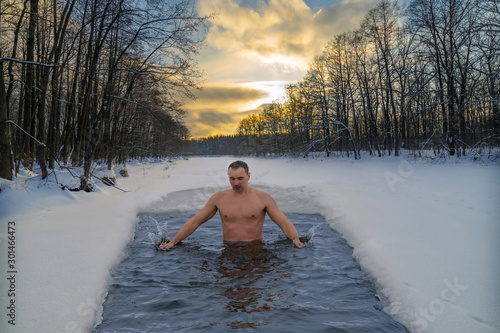 Winter swimming in cold water. Ice hole in the forest, extreme hardening of the body