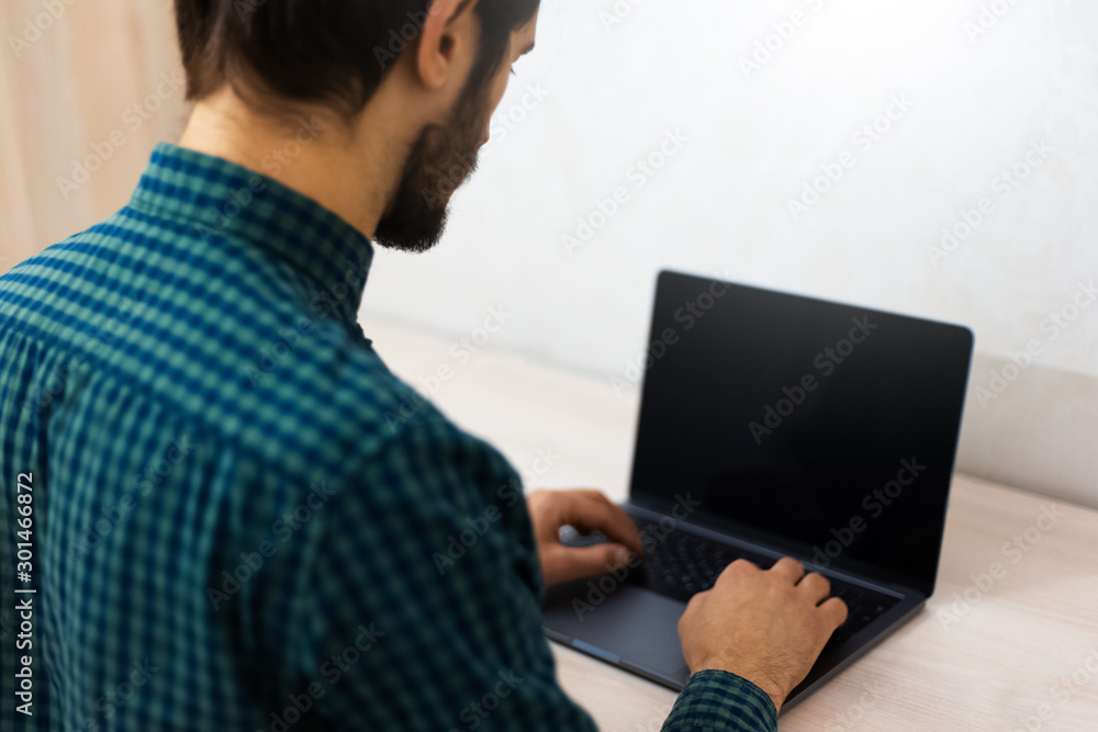 Back view of young man typing on laptop keyboard. Back view of young man typing on laptop keyboard.
