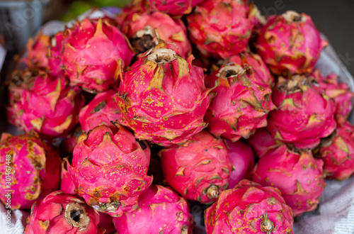 Many dragonfruits are stacked to form a nice pile. This pink fruit has white flesh with black seeds inside. It's a delicacy in Asia.