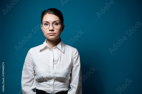 Canvas Print a girl with glasses and a white shirt, a shirt looks emotionless in front of herself