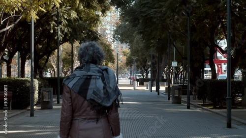 Mujer caminando por un camino de arboles junto a un pequeño perro