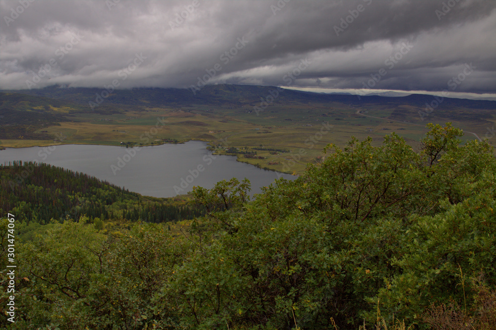 Storm clouds forming coming across the mountain range in early fall with a lake in the foreground