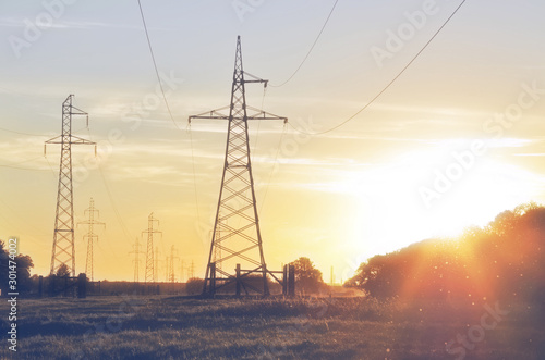 Steel power lines on a rural field in the evening at sunset