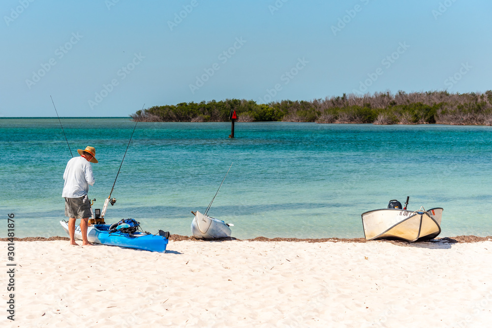 Boat and kayaks at Sombrero Beach in the Florida Keys. Man about to go fishing in the turquoise water of Biscayne Bay Boat and kayaks at Sombrero Beach in the Florida Keys. Man about to go fishing in the turquoise water of Biscayne Bay