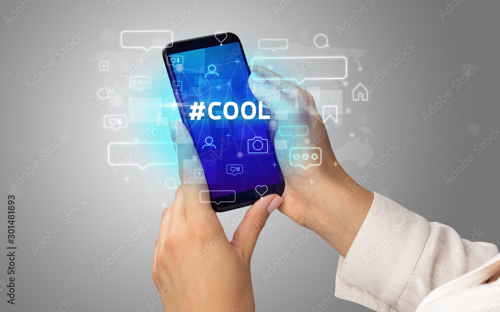 Female hand typing on smartphone with #COOL inscription, social media concept Female hand typing on smartphone with #COOL inscription, social media concept
