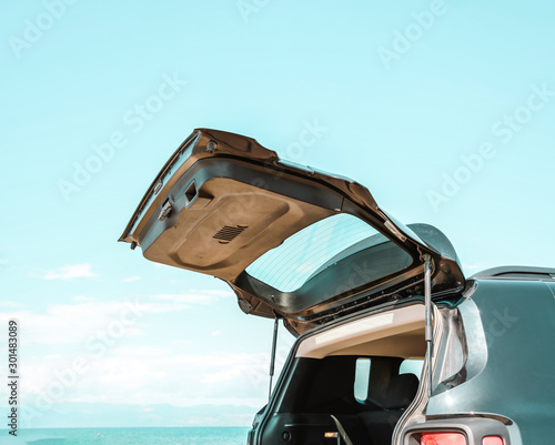 Black large car with an open luggage carrier parked on the beach. Sea landscape and free space for your product or text. Summer and sunny warm day. Copy space.