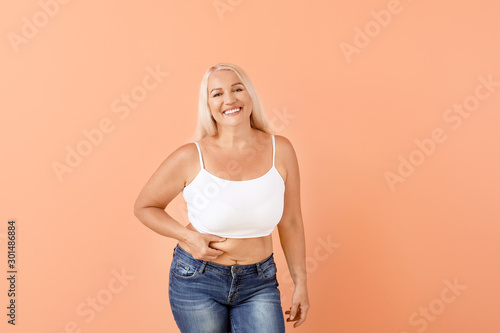 Portrait of mature body positive woman on color background