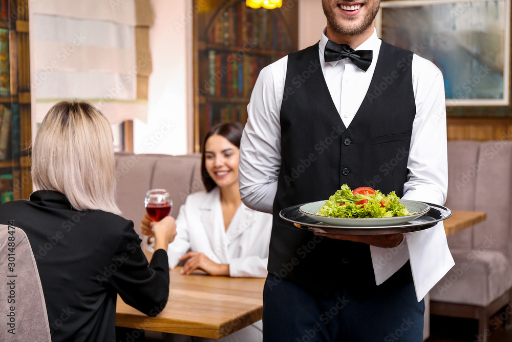 Young male waiter with salad in restaurant Young male waiter with salad in restaurant