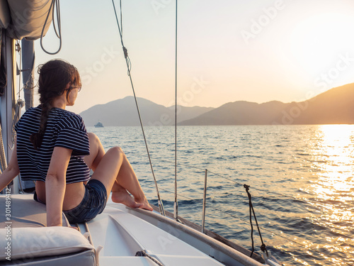 attractive young woman in a striped t-shirt enjoys the sunset on the deck of a sailing yacht. Sailing regatta © Alexander