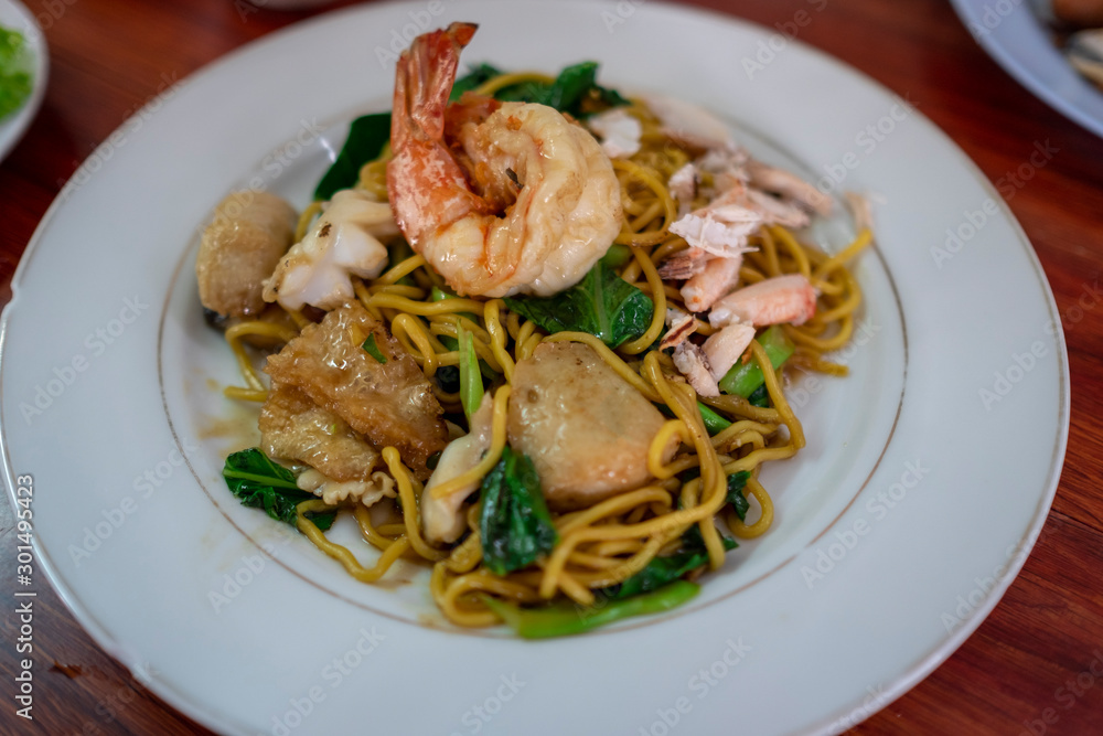 Stired fried yellow noodles with shrimp on white plate , top view, Chinese food, thai food, asian food.