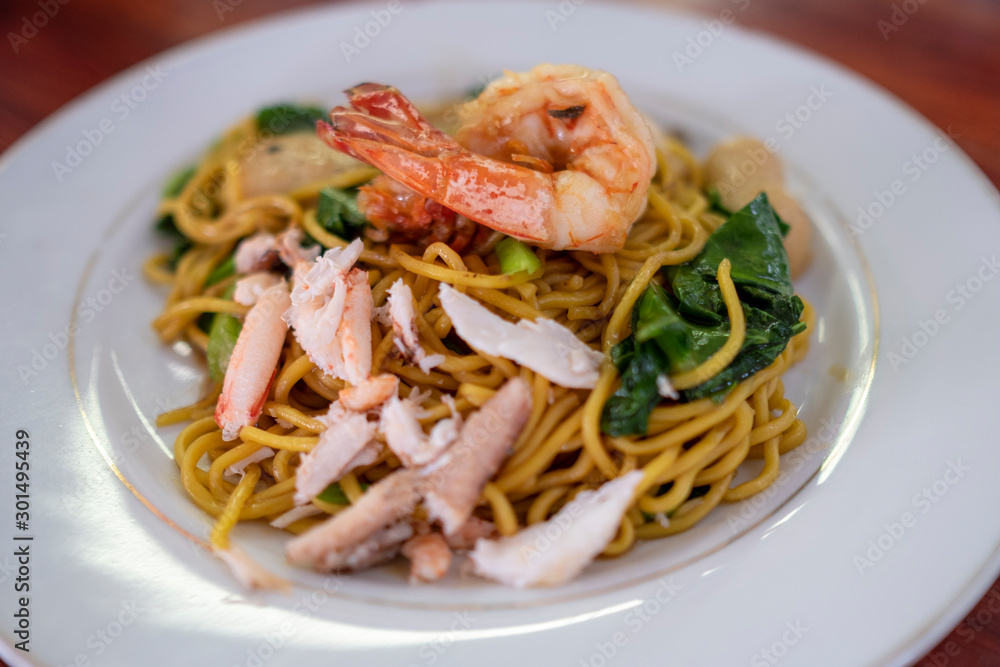 Stired fried yellow noodles with shrimp on white plate , top view, Chinese food, thai food, asian food.