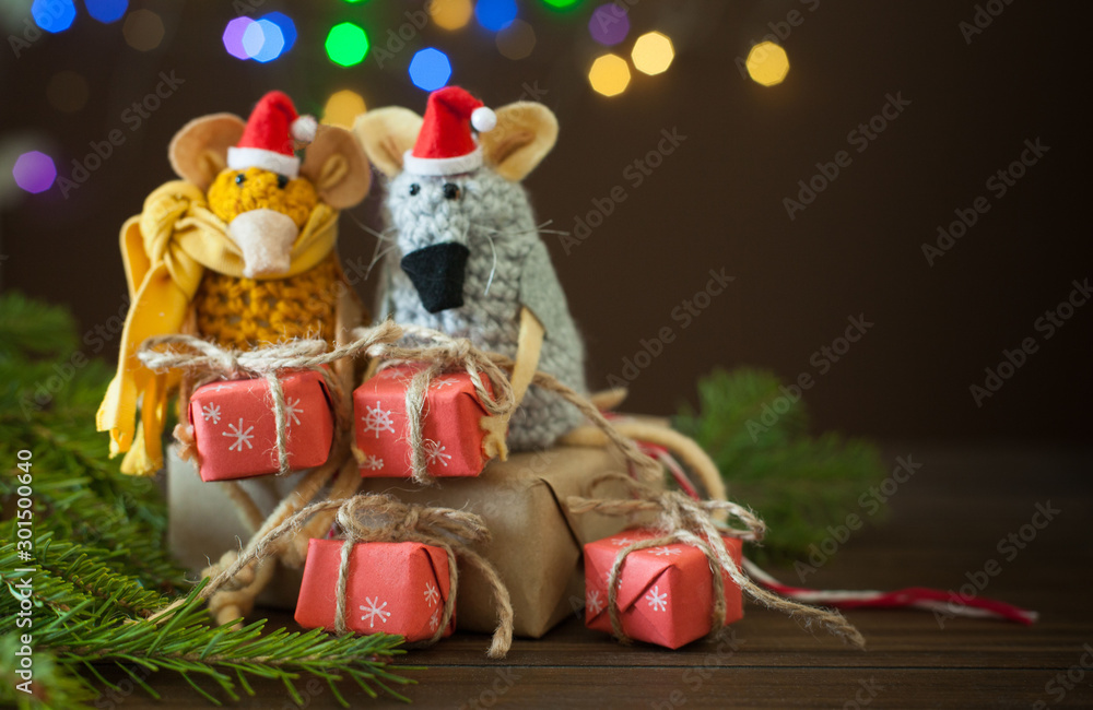 Rats knitted from yarn in Christmas caps. Gift boxes, spruce branches and Christmas garland. Rats knitted from yarn in Christmas caps. Gift boxes, spruce branches and Christmas garland.