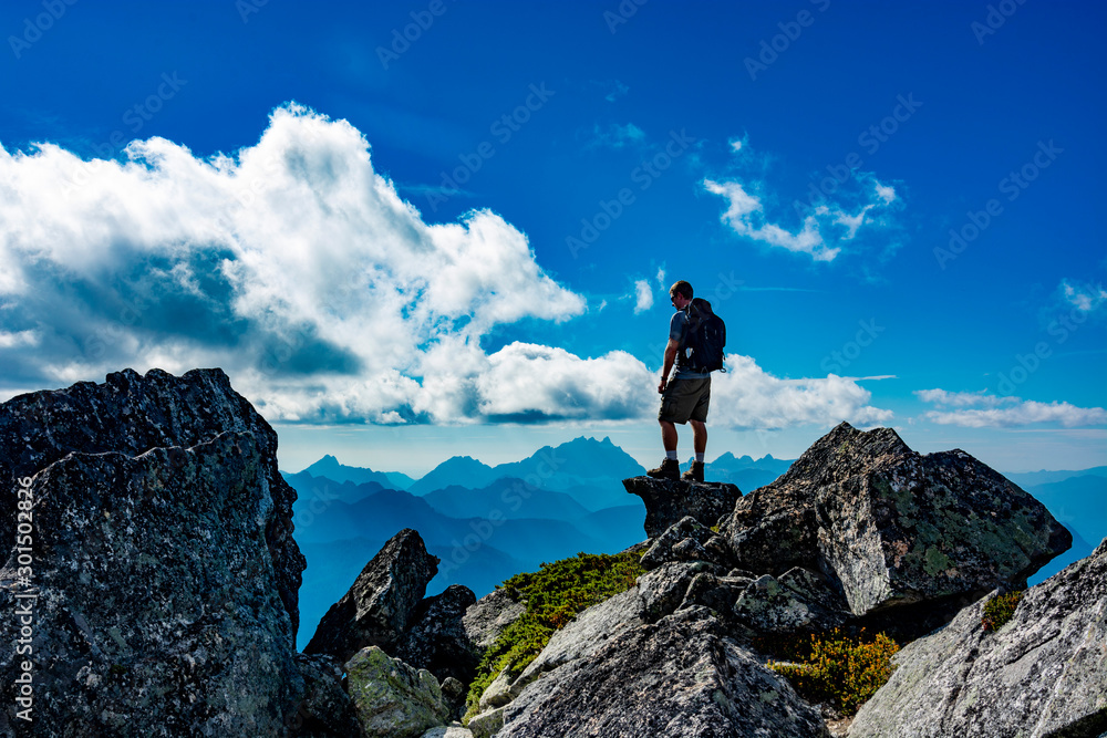 Adventurous man standing on top of a mountain.
