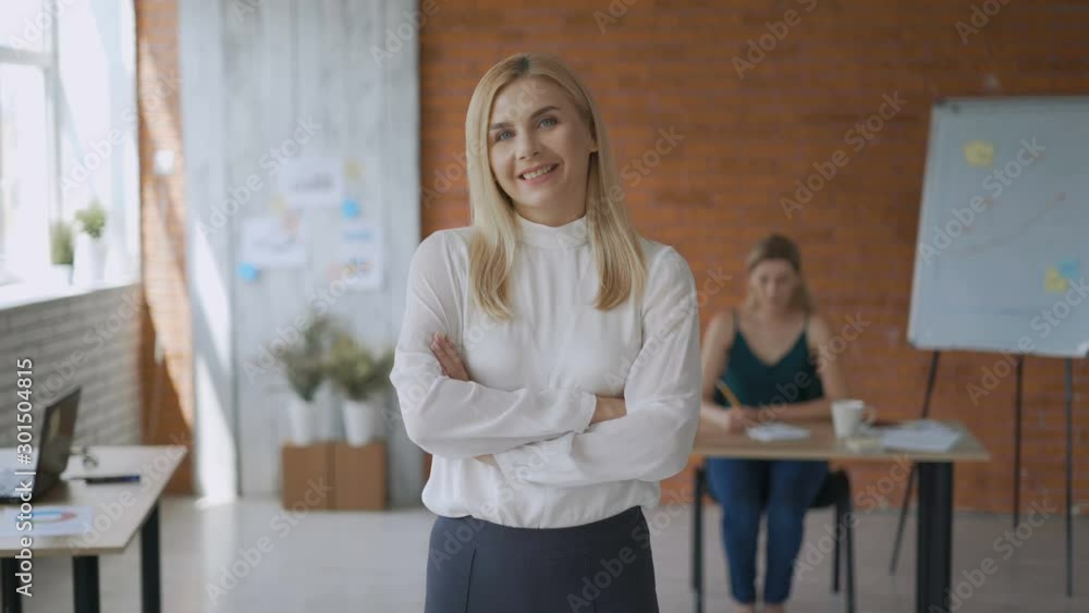 portrait of a successful girl medium shot, friendly woman smiling looking at the camera with her arms crossed. modern office 4K portrait of a successful girl medium shot, friendly woman smiling looking at the camera with her arms crossed. modern office 4K